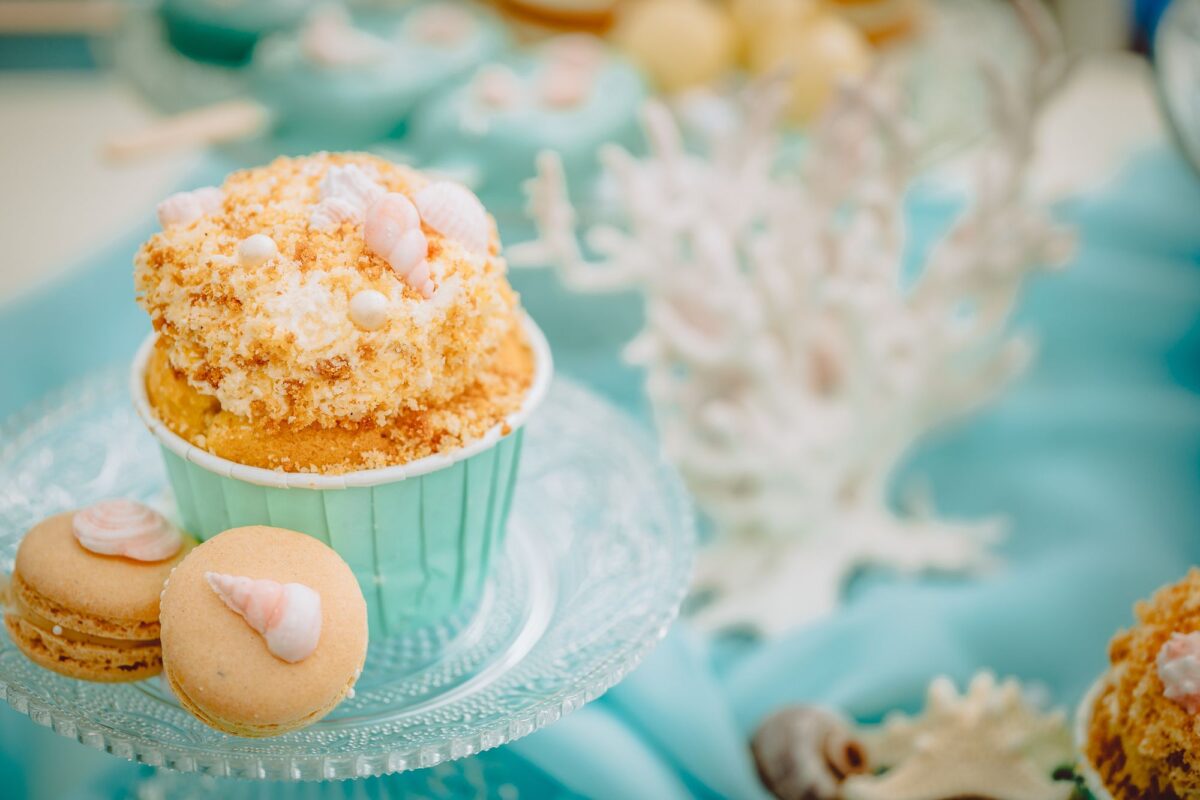 Cupcakes mit Muscheln und Muscheln auf einer blauen Tischdecke.