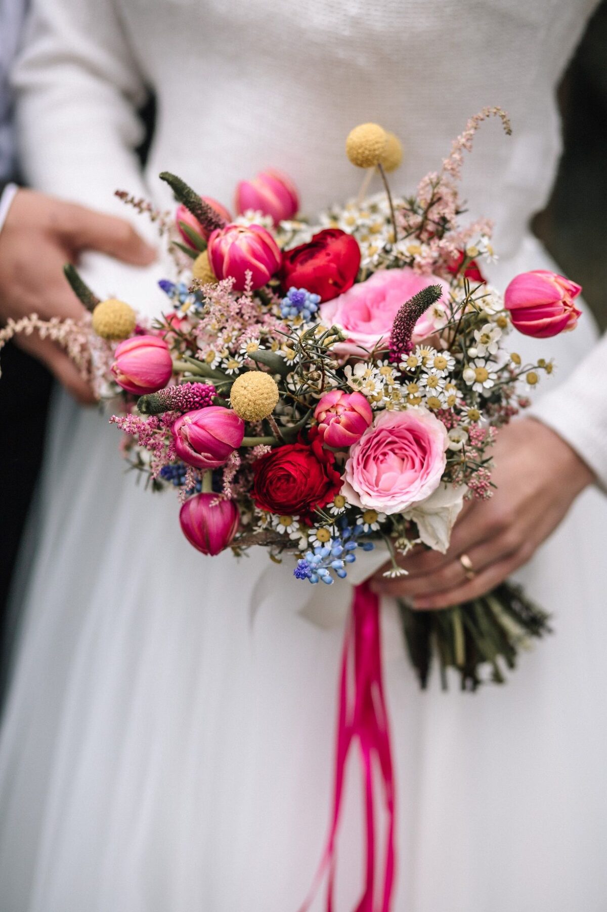 Eine Braut und ein Bräutigam halten einen Blumenstrauß in der Hand.