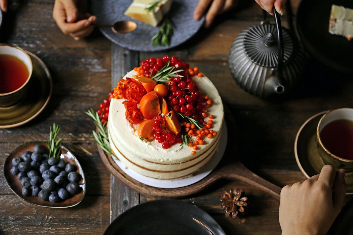 Ein Kuchen mit Beeren und Blaubeeren auf einem Holztisch.