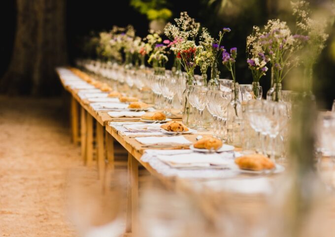 Ein langer Tisch mit Blumen und Brot.