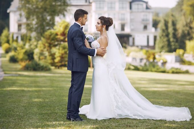 Eine Braut und ein Bräutigam stehen vor einer Villa.