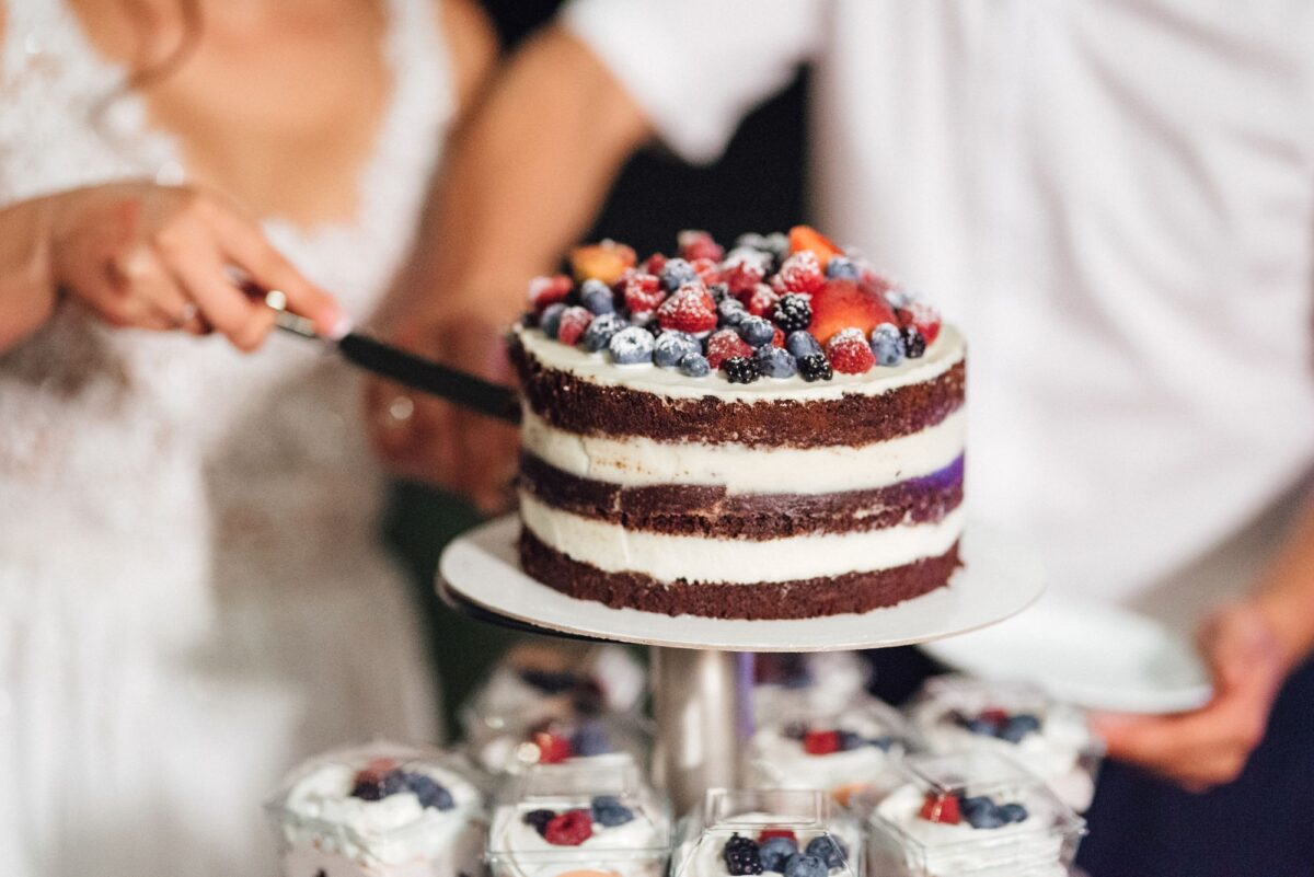 Eine Braut und ein Bräutigam schneiden eine Hochzeitstorte an.