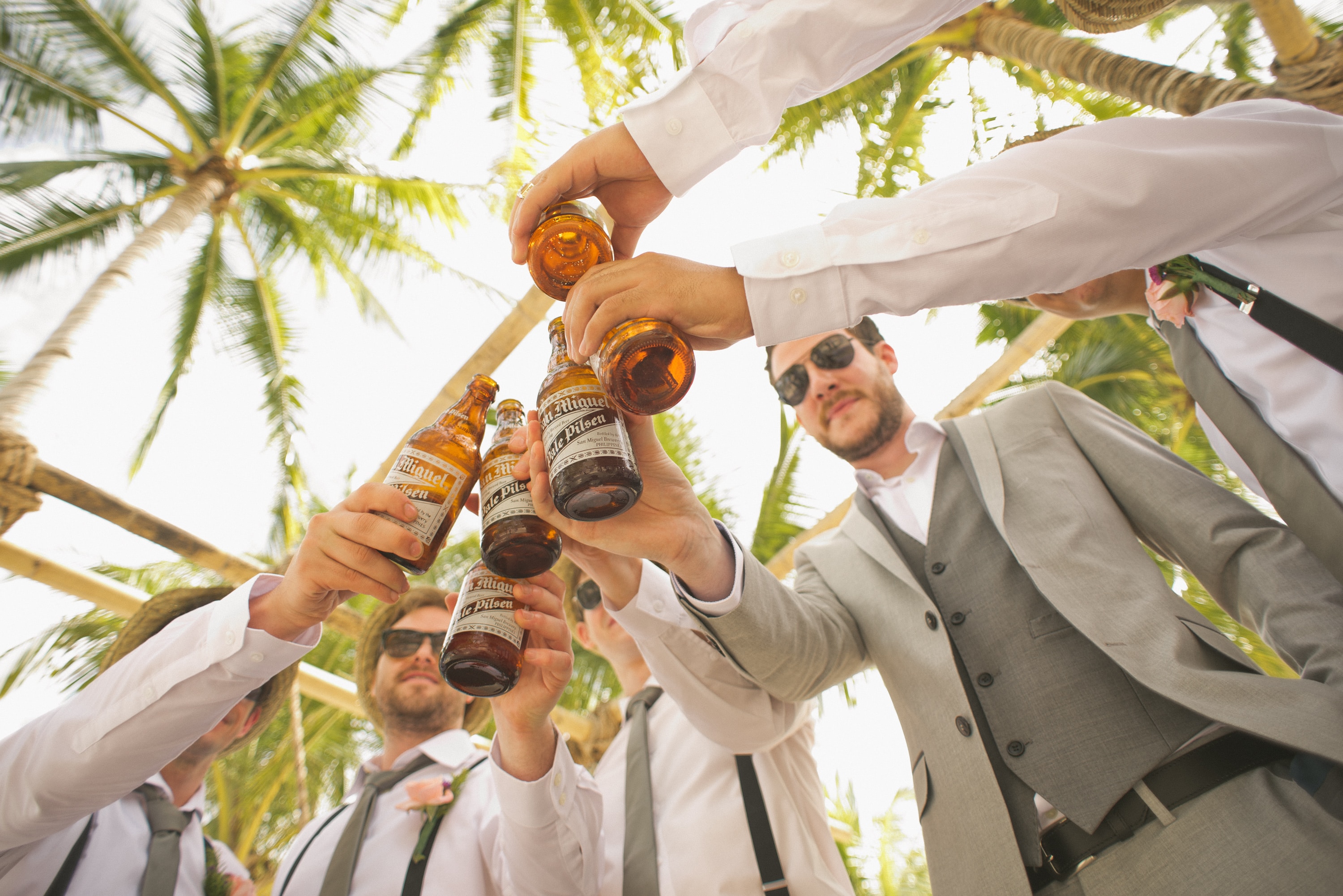 Eine Gruppe Trauzeugen prostet auf eine Flasche Bier an.