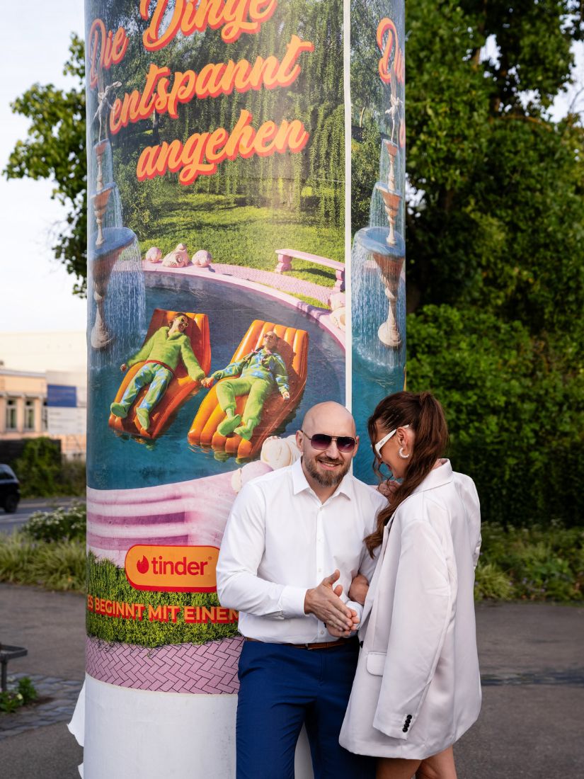 Das Brautpaar steht vor einer Litfaßsäule.